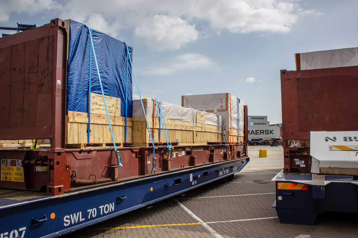 Flat rack üzerinde ağır iş makinesinin zincirlerle sabitlendiği operasyon